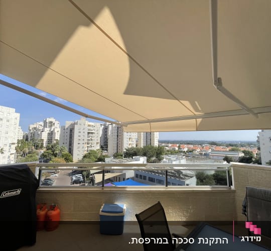 מרפסת עם סוכך פתוח ונוף עירוני ברקע